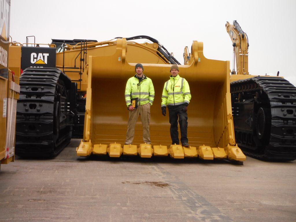 Wolfgang and Chris Bühn standing in a shovel of a CAT 6030
